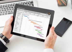 tablet z wykresami trzymany przez dłonie mężczyzny