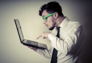 mężczyzna w białej koszuli trzymający laptopa
