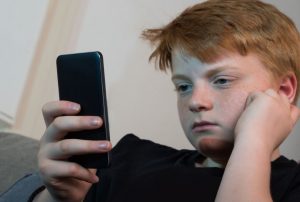chłopiec trzymający w dłoni telefon komórkowy