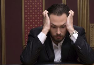 Młody zmartwiony mężczyzna pochylony nad stołem pokerowym