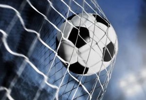 piłka w bramce na tle oświetlonego stadionu piłkarskiego