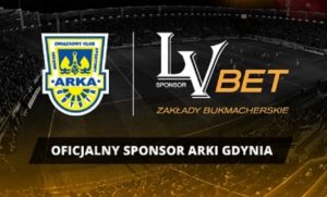 logo LVbet Zakłady Bukmacherskie i Arki Gdynia na tle boiska sportowego