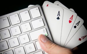 dłoń trzymająca karty do gry i klawiaturę komputerowa